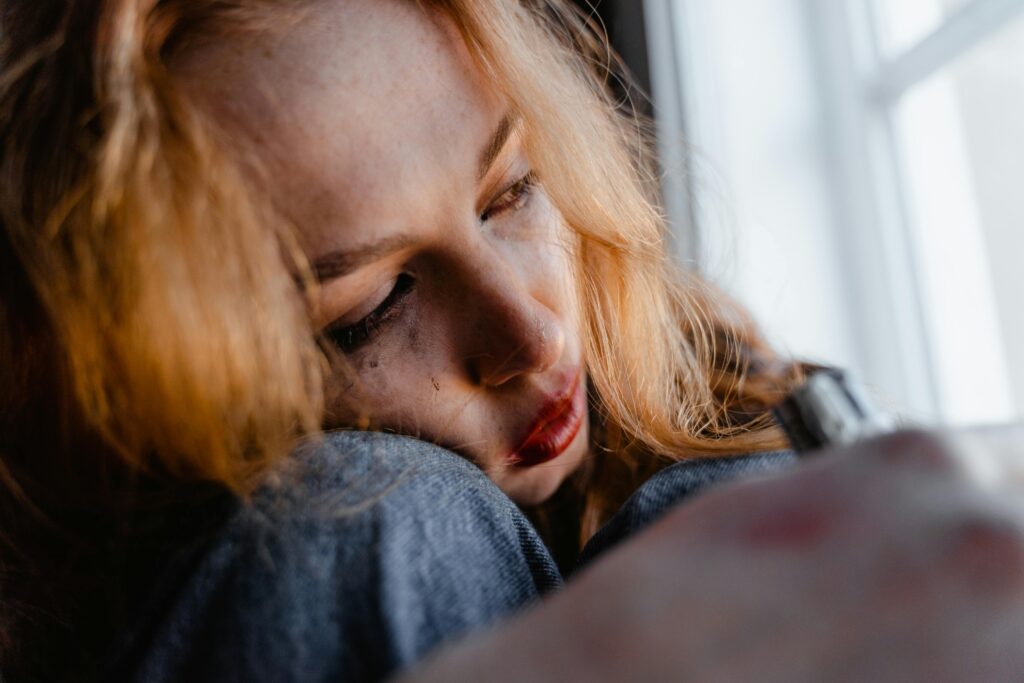Mulher sentada perto da janela refletindo sobre sua dependência emocional